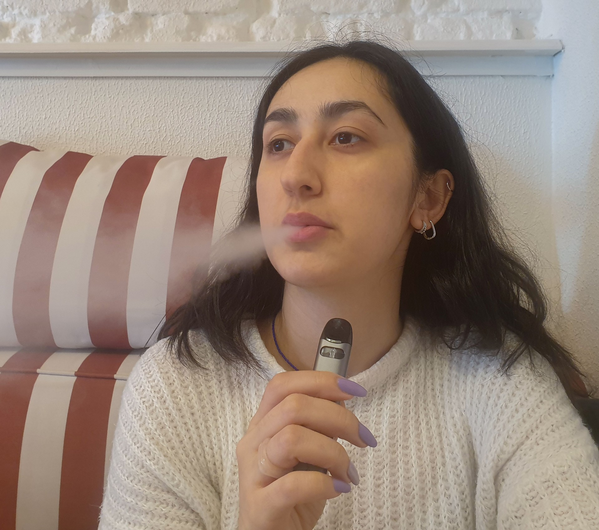 Woman vaping and exhaling cloud of smoke